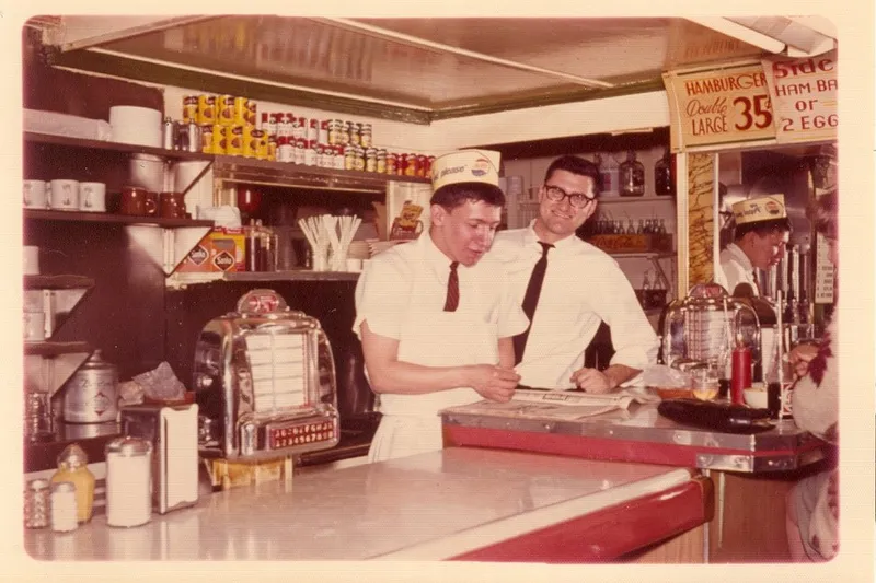 Vintage photo of countermen behind the counter at Sam's No. 3, with a jukebox in the foreground
