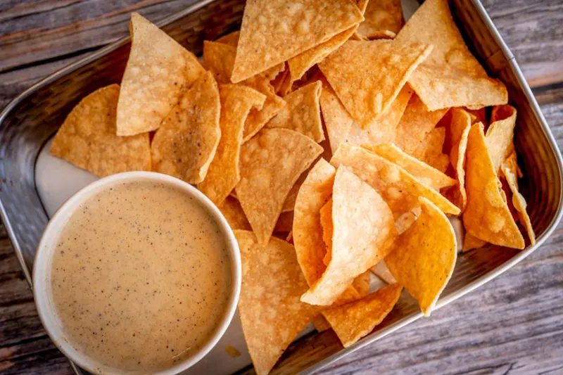 Basket of tortilla chips with a cup of queso at HiFi Burritos