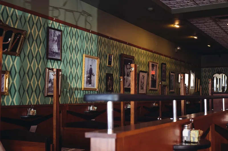 Vintage photo-lined dining room wall and booths at Perly's Restaurant & Delicatessen