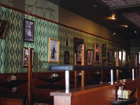 Vintage photo-lined dining room wall and booths at Perly's Restaurant & Delicatessen