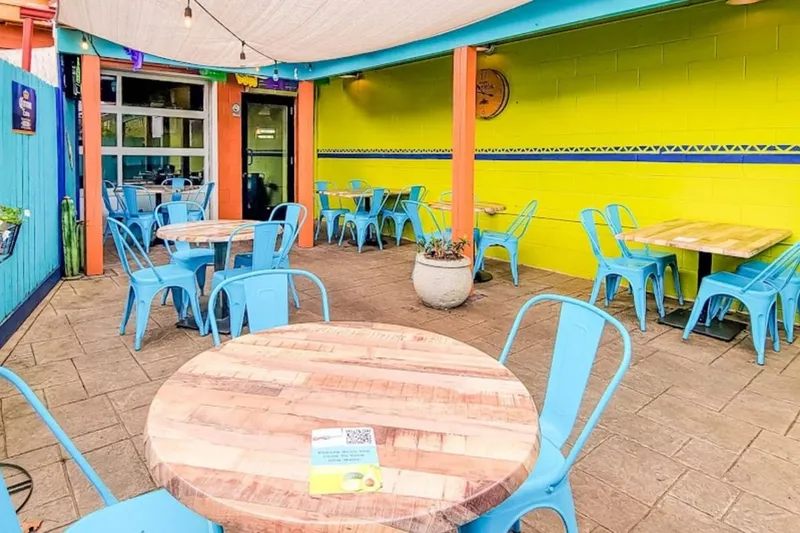 Turquoise patio tables against a yellow wall at Cuco's Taqueria