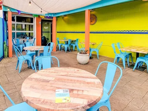 Turquoise patio tables against a yellow wall at Cuco's Taqueria