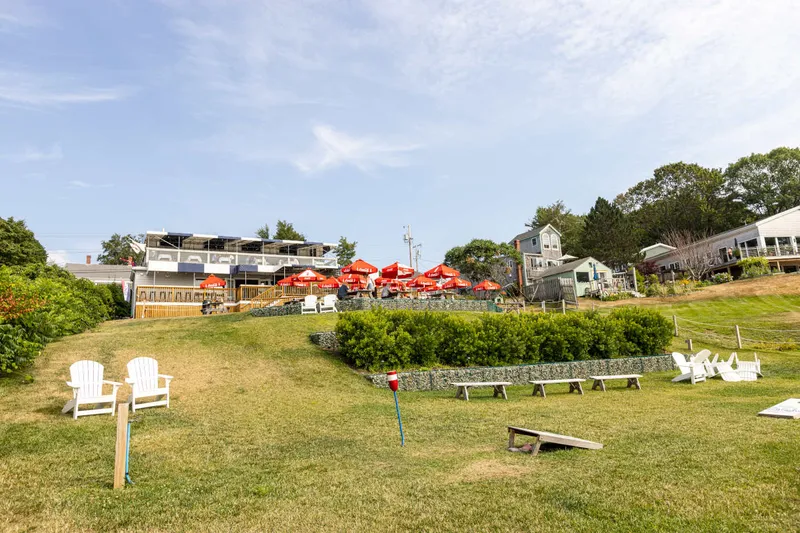 Lawn with Adirondack chairs looking toward the red umbrellas of Island Lobster Company on Peaks Island