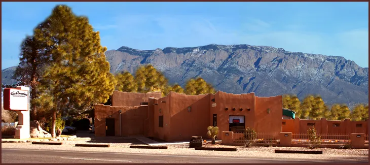 Exterior of the adobe Casa de Benavidez restaurant with its sign, set against the Sandia Mountains in Albuquerque, New Mexico