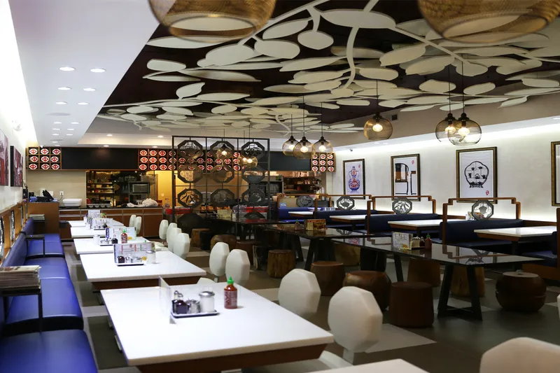 Dining room with blue booths and a leaf-patterned ceiling at Chi Cafe in Chinatown