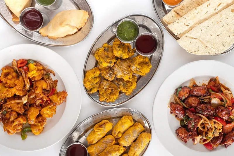An overhead spread of appetizers at New Taste of India in Portland: samosas, pakoras, papadums, gobi manchurian and chili chicken