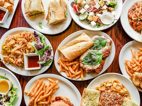 Sandwiches, salads and pasta plates covering a wooden table at The Hammer Pub and Grill