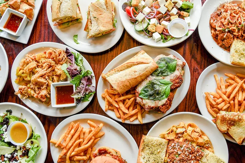 Sandwiches, salads and pasta plates covering a wooden table at The Hammer Pub and Grill