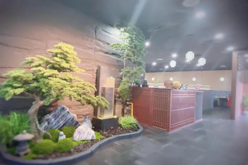 Interior of Hiya Chili in Tulsa, with a bonsai-and-rock garden feature beside a red lattice host counter under hanging Chinese lanterns