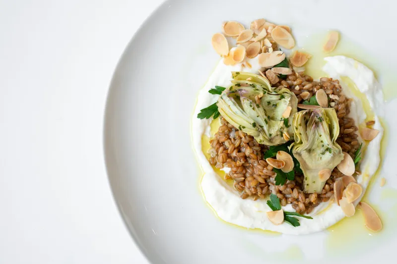 Nordic farro dish with artichokes, whipped cheese and toasted almonds on a white plate at FIKA Café, American Swedish Institute