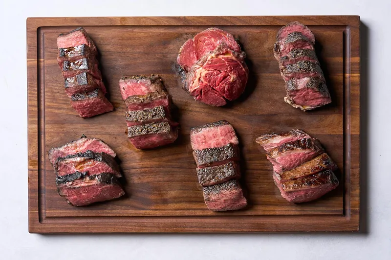 A walnut carving board topped with an assortment of sliced cooked steaks at Bardea Steak in Wilmington