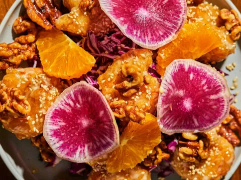 Walnut shrimp with orange slices, red cabbage, candied walnuts, sesame seeds, and watermelon radish slices
