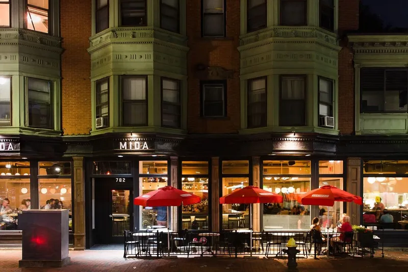 Illuminated MIDA South End storefront and patio seating at night