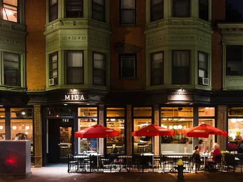 Illuminated MIDA South End storefront and patio seating at night