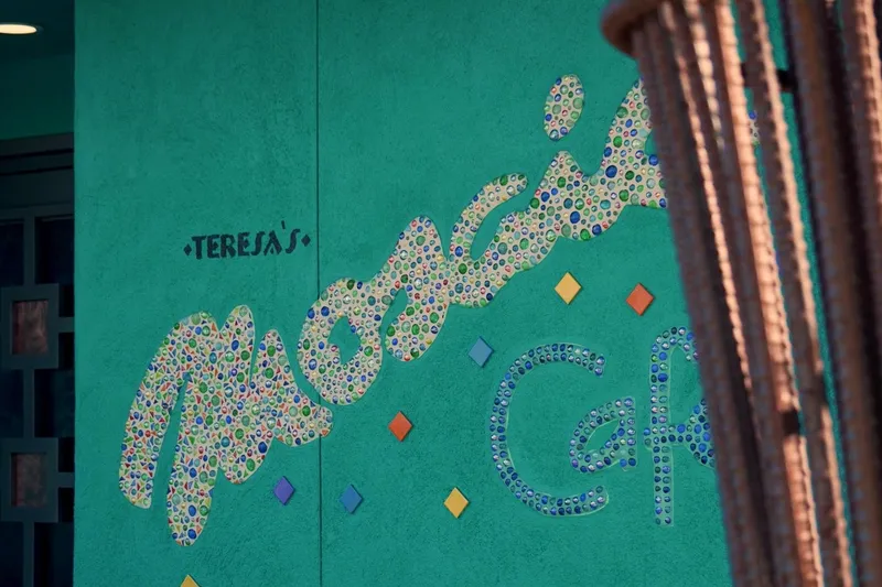 The teal exterior wall of Teresa's Mosaic Cafe in Tucson with the restaurant's name spelled out in colorful glass-tile mosaic lettering beside the entrance