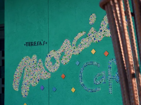 The teal exterior wall of Teresa's Mosaic Cafe in Tucson with the restaurant's name spelled out in colorful glass-tile mosaic lettering beside the entrance