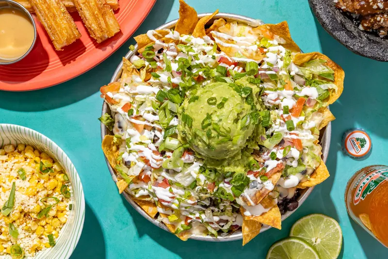 Overhead spread of loaded nachos topped with guacamole, street-corn elote, churros and carnitas at Taco Boy in Charleston, South Carolina