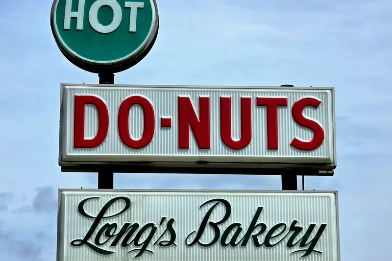 "Hot Do-Nuts, Long's Bakery" sign against a blue sky