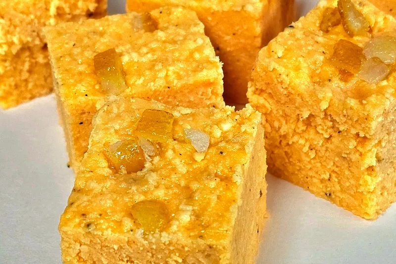 Squares of orange barfi topped with candied fruit, an Indian sweet from Surati Farsan Mart