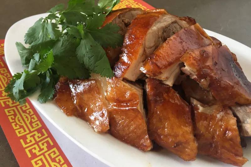 Plate of sliced Cantonese roast duck with crispy skin and fresh cilantro at First Chinese BBQ in Richardson