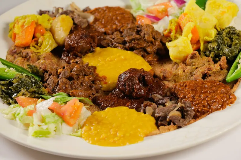 An Ethiopian combination platter at Messob with beef and vegetable stews, collard greens, salad and jalapeños served over injera