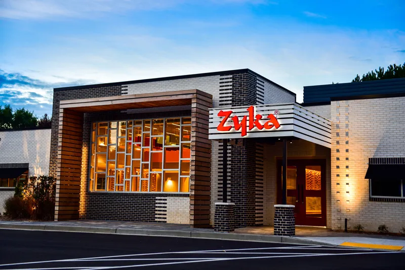 Zyka: The Taste storefront at dusk with the illuminated red Zyka sign over the entrance in Decatur, Georgia