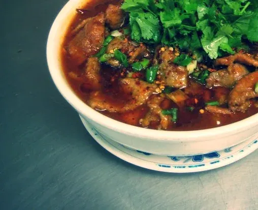Sichuanese Boiled Beef, a spicy chili-oil stew topped with cilantro, served in a bowl at Sichuanese Cuisine in Seattle