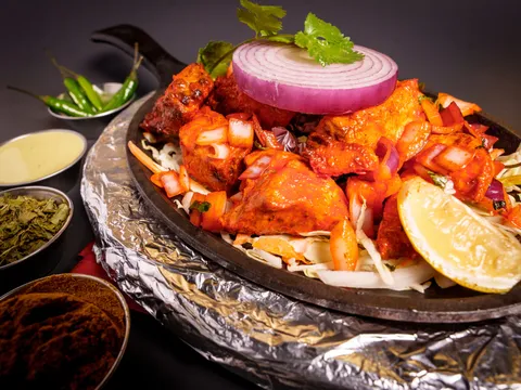 Sizzling tandoori mixed grill of chicken tikka and kebabs topped with a grilled onion ring, with chutneys and spices alongside, at Maharaja Indian Cuisine in Omaha