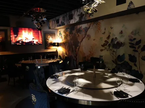 Dining room at Blackbrick in Hyde Park, Tampa, with round marble tables and lazy Susans, velvet chairs and a floral-and-bird mural