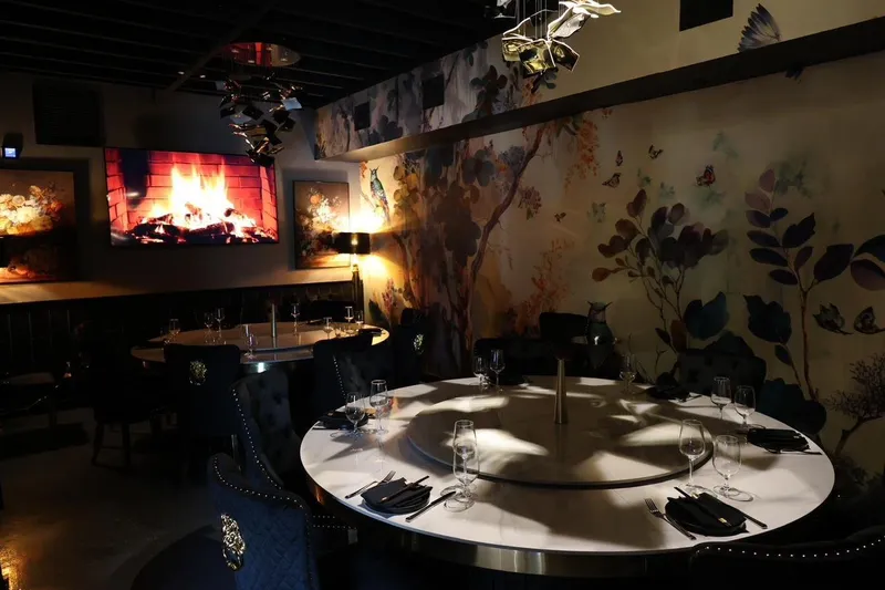 Dining room at Blackbrick in Hyde Park, Tampa, with round marble tables and lazy Susans, velvet chairs and a floral-and-bird mural