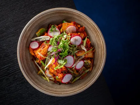 Bowl of chicken chilli garnished with radish, scallion and cilantro at Vajra