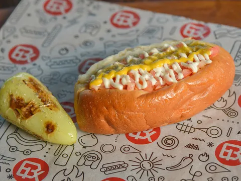 BK's award-winning Sonoran hot dog wrapped in bacon and topped with beans, onions, tomato, mayo and mustard, with a grilled yellow pepper, on BK-logo paper