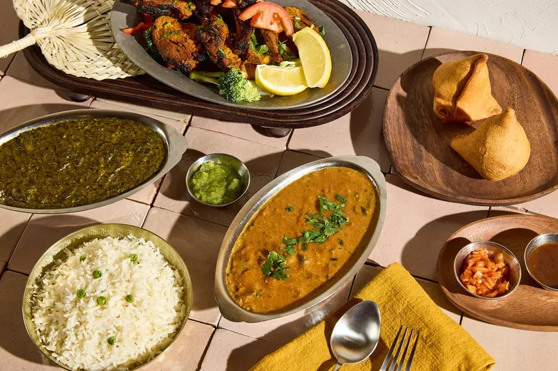 Spread of Indian dishes at Aab India Restaurant including a tandoori platter, saag, dal makhani, basmati rice, samosas and chutneys