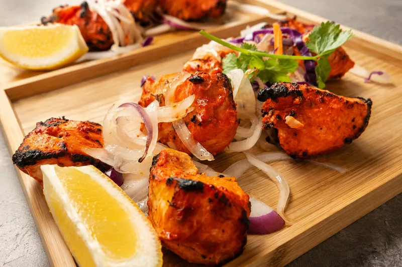 Tandoori chicken pieces with onions, cilantro, and lemon at Cumin Lakeview