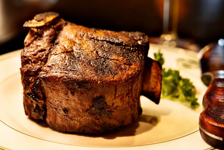 Thick-cut charred steak plated with parsley at Manny's Steakhouse in Minneapolis
