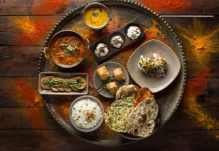 Indian thali platter at Bombay Grill with curry, rice, breads, raita and chutneys arranged on a metal tray