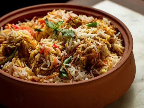 Biryani in a terracotta pot topped with mint, saffron rice, and crispy onions at GupShup