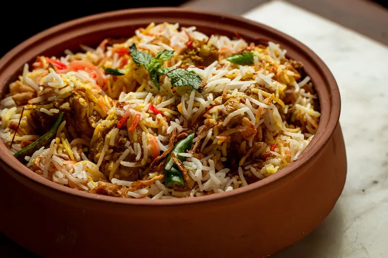 Biryani in a terracotta pot topped with mint, saffron rice, and crispy onions at GupShup
