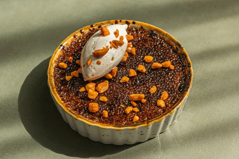 Crème brûlée dessert with spiced pecan crumble and quenelle of cream at Common Thread in Savannah
