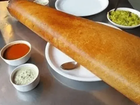 A large crispy dosa served with sambar and coconut and tomato chutneys at Samburna Indian Restaurant in Bothell