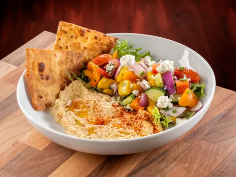Bowl of hummus drizzled with olive oil and paprika, served with toasted pita wedges and a chopped vegetable salad, at Union Grill in Pittsburgh