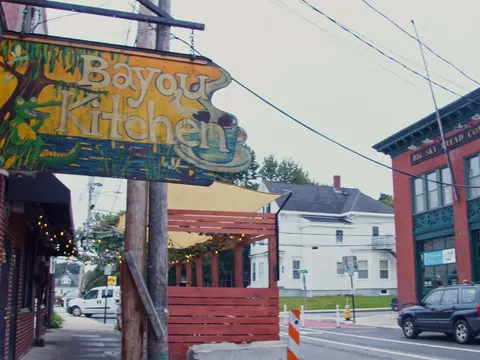Carved wooden sign for The Bayou Kitchen hanging over a Portland street corner