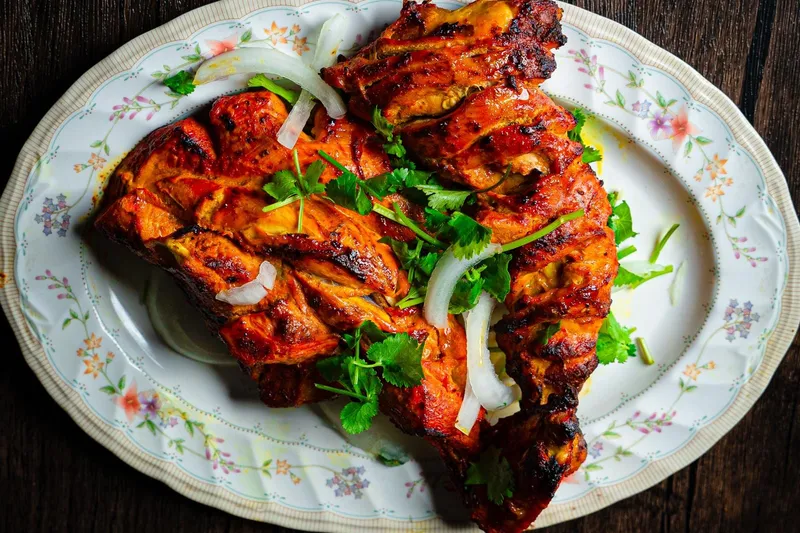 Platter of tandoori chicken with sliced onion and cilantro at Shalimar