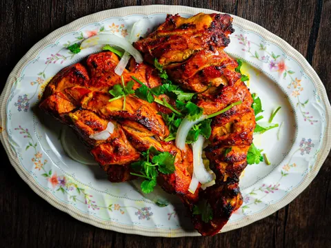 Platter of tandoori chicken with sliced onion and cilantro at Shalimar