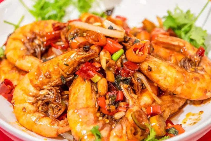 House-special spicy sautéed shrimp with red chilies, peppers and cilantro on a white plate at Red Chili Hunan Restaurant