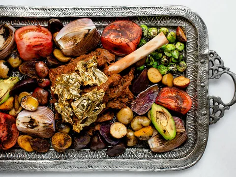 Slow-cooked lamb shank with gold leaf, charred vegetables and potatoes on an engraved silver platter at Rania