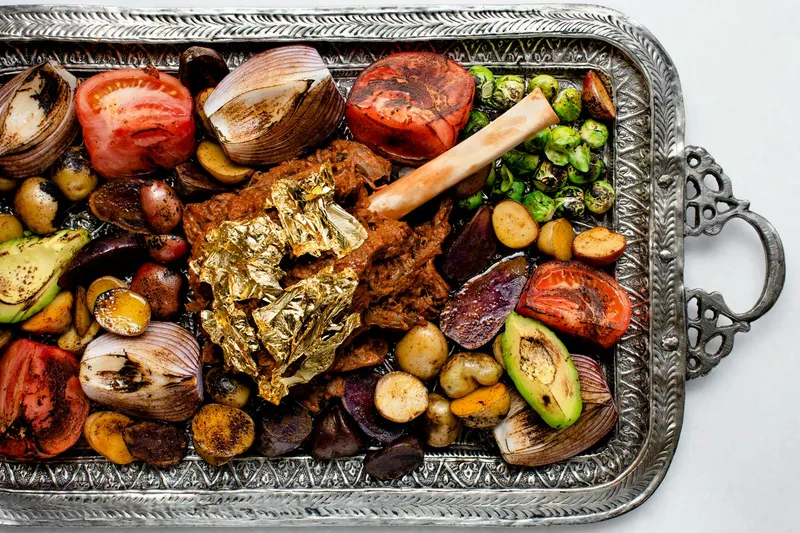 Slow-cooked lamb shank with gold leaf, charred vegetables and potatoes on an engraved silver platter at Rania
