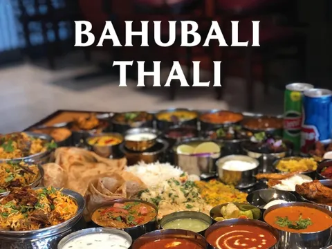 A large Bahubali Thali platter at Godavari Cincinnati filled with an assortment of biryanis, curries, dal, raita, papad, rice and breads in steel bowls