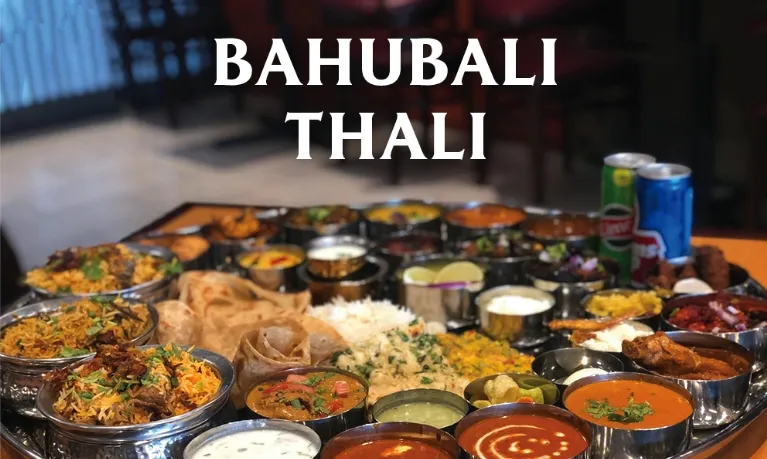 A large Bahubali Thali platter at Godavari Cincinnati filled with an assortment of biryanis, curries, dal, raita, papad, rice and breads in steel bowls