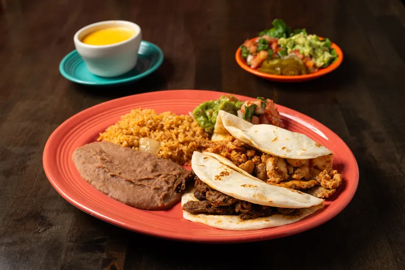 Fajita taco plate with beef and chicken fajita flour tacos, Mexican rice, refried beans and guacamole at Henry's Puffy Tacos